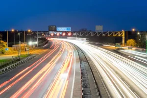 M2M smart highway at night with light trails showing connected IoT traffic systems