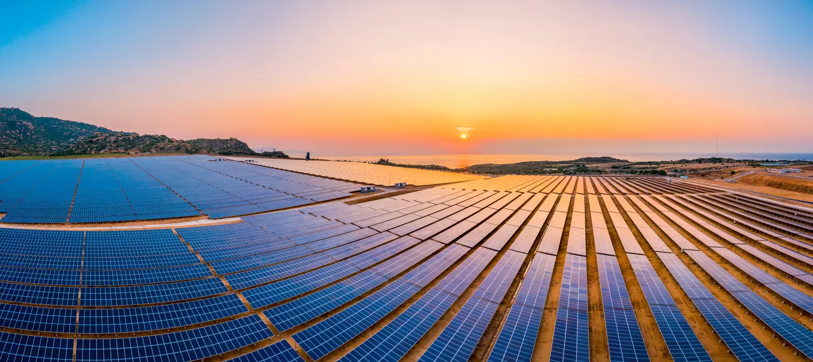 Aerial view of a solar farm with rows of photovoltaic panels, optimized by IoT sensors for real-time performance monitoring.